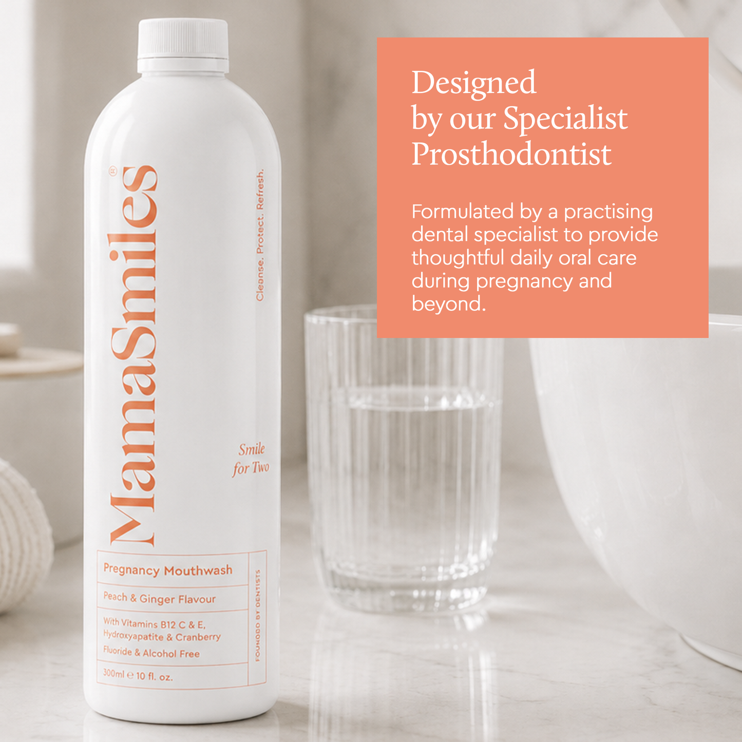A white bottle of MamaSmiles Pregnancy Mouthwash with orange text, shown next to a glass of water and a white bowl on a light marble surface. An orange text box on the right reads 'Designed by our Specialist Prosthodontist'.
