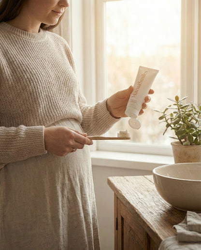Woman holding MamaSmiles toothpaste in a bathroom.